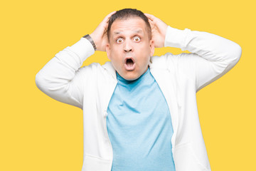 Middle age arab man wearing sweatshirt over isolated background Crazy and scared with hands on head, afraid and surprised of shock with open mouth