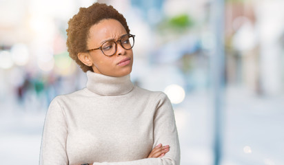 Young beautiful african american woman wearing glasses over isolated background smiling looking to the side with arms crossed convinced and confident