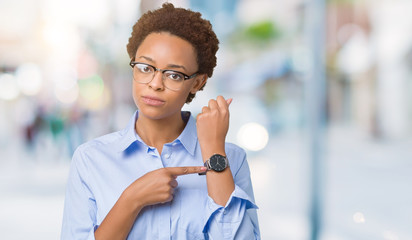 Young beautiful african american business woman over isolated background In hurry pointing to watch...