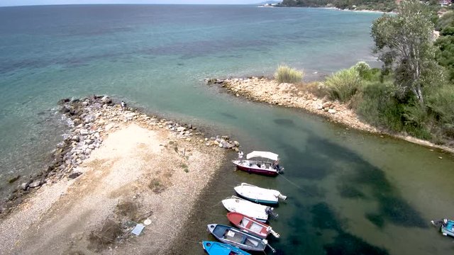 Aerial view of small natural harbor with barges  in the area of Agia Paraskevi Halkidiki, Greece, move forward by drone