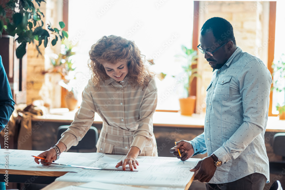 Canvas Prints Curly red-haired woman helping colleague to draw sketches