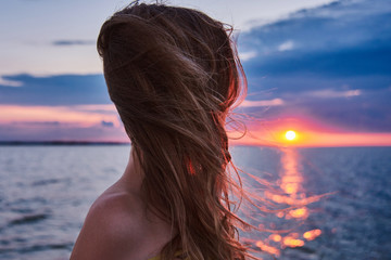 Portrait of young slim girl on sunset in the sea. Young woman meets sunrise on boat