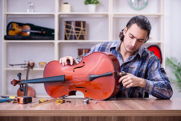 Young handsome repairman repairing violin