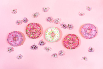 Top view pattern of five glazed donuts and flowers of lilac. 