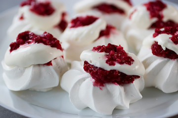 Homemade dessert Pavlova with raspberries on a white plate on a gray table.