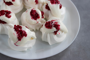 Homemade dessert Pavlova with raspberries on a white plate on a gray table.