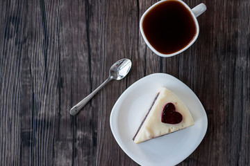 Gluten-free and sugar-free vegan cake on a white plate and white sashka coffee on a brown wooden table.