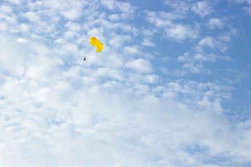 people flying on a yellow parachute in the sky