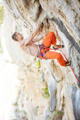 Young man climbing challenging route on overhanging cliff