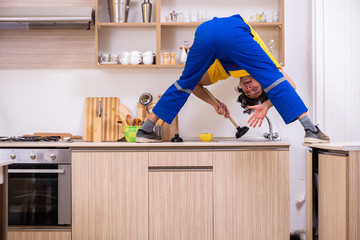 Young male contractor repairing tap at home 