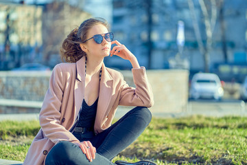 girl in a pink coat sits on the grass