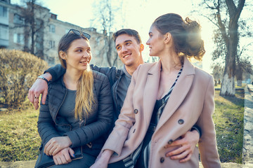 a guy with two girls. sitting on a bench