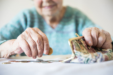 Detailed closeup photo of elderly 96 years old womans hands counting remaining coins from pension...