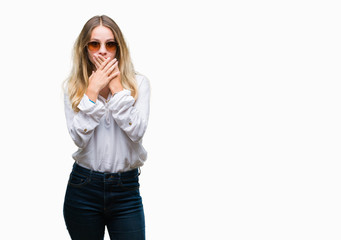 Young beautiful blonde woman wearing sunglasses over isolated background shocked covering mouth with hands for mistake. Secret concept.