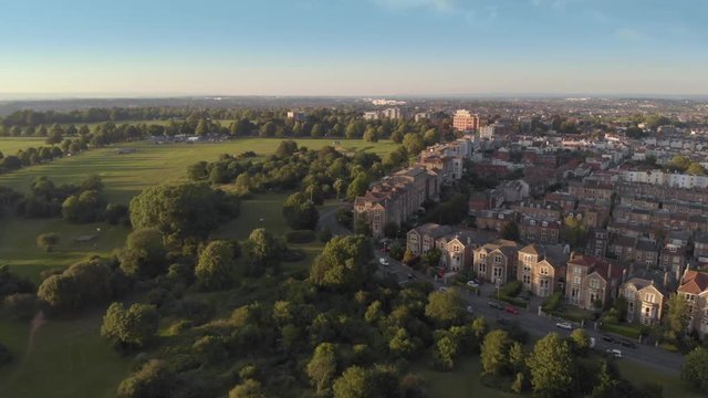 Aerial flyover green tree lined city streets of Bristol, England, drone shot at sunset  golden hour