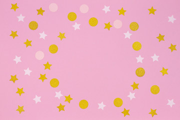 Festive pink background. Colorful confetti and golden stars on light pink background. Top view