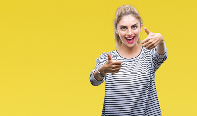 Young beautiful blonde woman wearing stripes sweater over isolated background approving doing positive gesture with hand, thumbs up smiling and happy for success. Looking at the camera