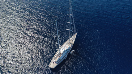 Naklejka premium Aerial drone photo of modern sail boat docked in bay of Ornos in deep blue Aegean sea, Mykonos island, Cyclades, Greece