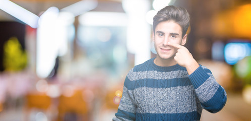 Young handsome man over isolated background Pointing with hand finger to face and nose, smiling cheerful