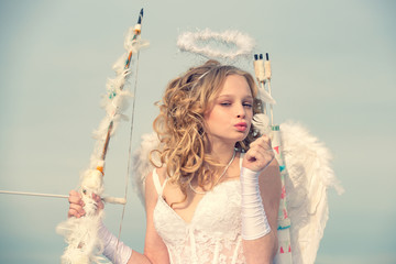 Child with angelic character. Happy teenage angel girl. Lovely girl cupid with bow and arrow is...