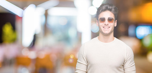 Fototapeta na wymiar Young handsome man wearing sunglasses over isolated background with a happy and cool smile on face. Lucky person.