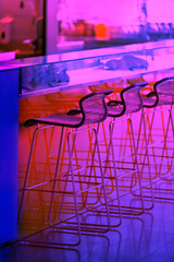Neon colored Empty row of stools at a bar