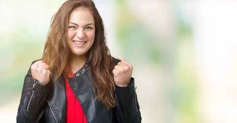 Beautiful plus size young woman wearing a fashion leather jacket over isolated background excited for success with arms raised celebrating victory smiling. Winner concept.