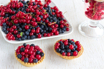 Basket-shaped cookies and plate with with red currants and blueberries  berries. White background.