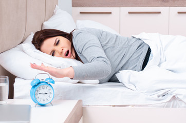 Young woman lying on the bed in time management concept 