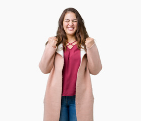 Obraz na płótnie Canvas Beautiful plus size young woman wearing winter coat over isolated background excited for success with arms raised celebrating victory smiling. Winner concept.