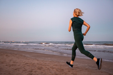 Beautiful people Fitness woman with short blonde hair running in a sea beach side . Sport and Healthy Lifestyle Concept