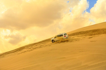 Desert safari adventure. 4x4 vehicle bashing dunes side to side through the desert dunes at sunset...