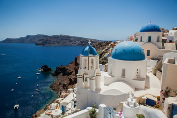 Oia town on Santorini island, Greece. View of traditional white houses and churches with blue domes over the Caldera