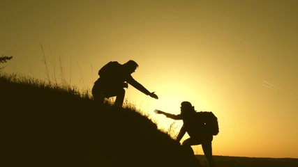 travelers climb the cliff holding hand. teamwork of business people. Happy family on vacation. traveler man extends his hand to a girl climbing to the top of hill. tourists hug on top of mountain