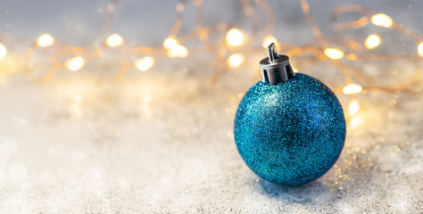 Blue christmas ball on glitter background. Christmas and happy new year concert for your design with space for text, banner. Garlands and bokeh light. Wallpaper 2020 new year.