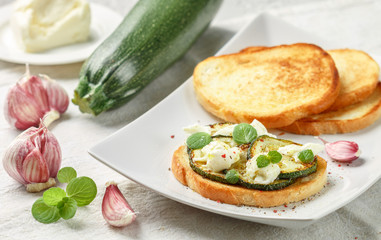 Delicacy bruschetta with fried or baked zucchini, mozzarella cheese, garlic, mint and spices. Mediterranean sandwich. Canape. Antipasti.  Delicious breakfast. Gourmet appetizer. Selective focus