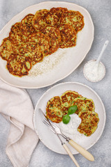 Fritters of zucchini with fresh parsley and Basil. Delicatessen vegetable pancakes with sauce from sour cream and dill. Selective focus