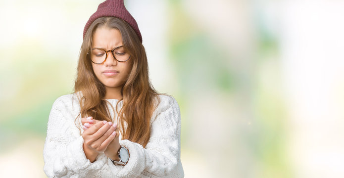 Young beautiful brunette hipster woman wearing glasses and winter hat over isolated background Suffering pain on hands and fingers, arthritis inflammation