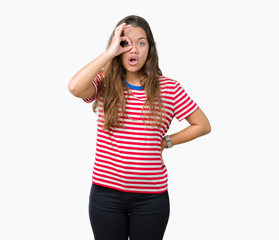 Obraz na płótnie Canvas Young beautiful brunette woman wearing stripes t-shirt over isolated background doing ok gesture shocked with surprised face, eye looking through fingers. Unbelieving expression.