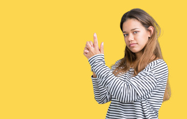 Young beautiful brunette woman wearing stripes sweater over isolated background Holding symbolic gun with hand gesture, playing killing shooting weapons, angry face