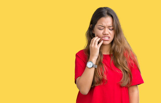 Young beautiful brunette woman wearing red t-shirt over isolated background touching mouth with hand with painful expression because of toothache or dental illness on teeth. Dentist concept.