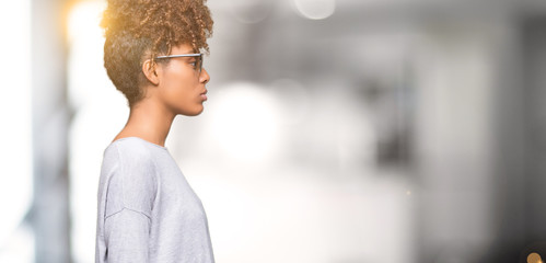 Beautiful young african american woman wearing sunglasses over isolated background looking to side,...