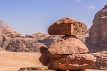 pile of stones balance construction center of composition on a desert sand and rocky mountains unfocused scenery landscape background 