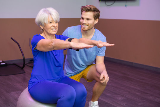senior woman doing exercise with coach pillates ball