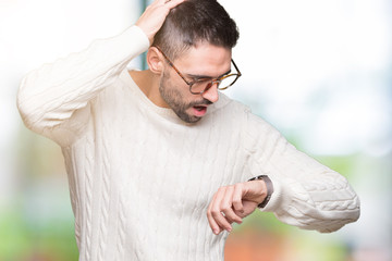 Young handsome man wearing glasses over isolated background Looking at the watch time worried,...
