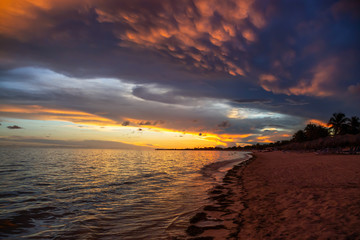 Fototapeta na wymiar Beautiful View of a sandy beach, Playa Ancon, on the Caribbean Sea in Triniday, Cuba, during a dramatic cloudy sunset.