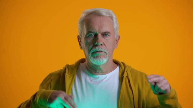 Elderly male mentalist demonstrating mind-reading power at camera, telepathy