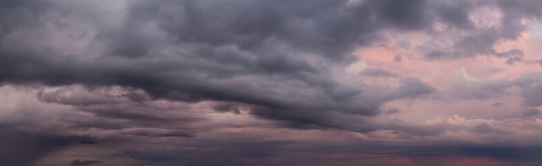 Dramatic Panoramic View of a cloudscape during a dark, rainy and colorful morning sunrise. Taken...