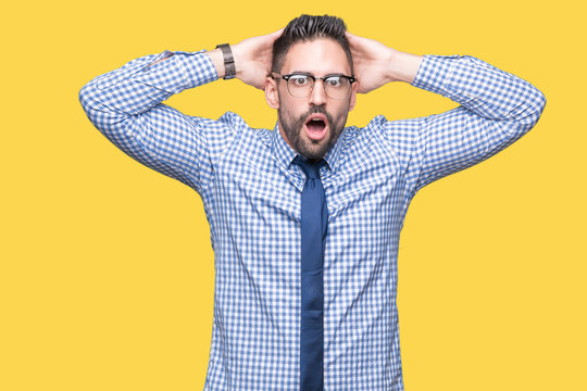 Young business man wearing glasses over isolated background Crazy and scared with hands on head, afraid and surprised of shock with open mouth