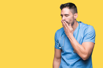 Handsome young doctor surgeon man over isolated background bored yawning tired covering mouth with...